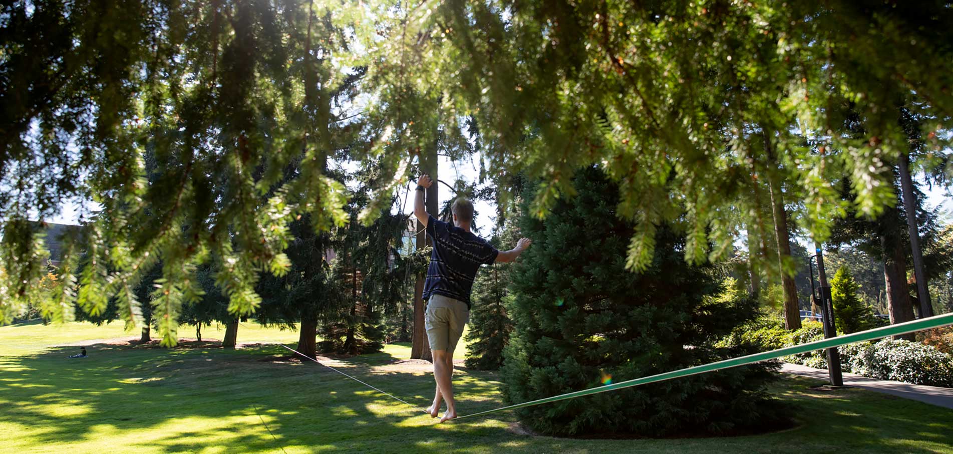 student walking on a tight rope on campus outside 