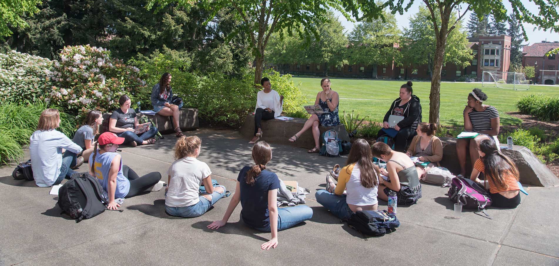 students sitting outside in a circle on campus